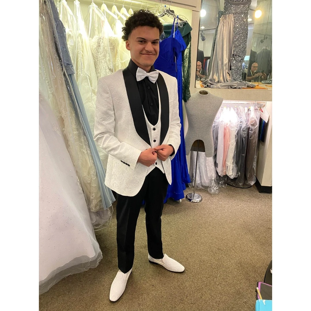 Client in white textured tuxedo with black lapel, matching vest and bow tie