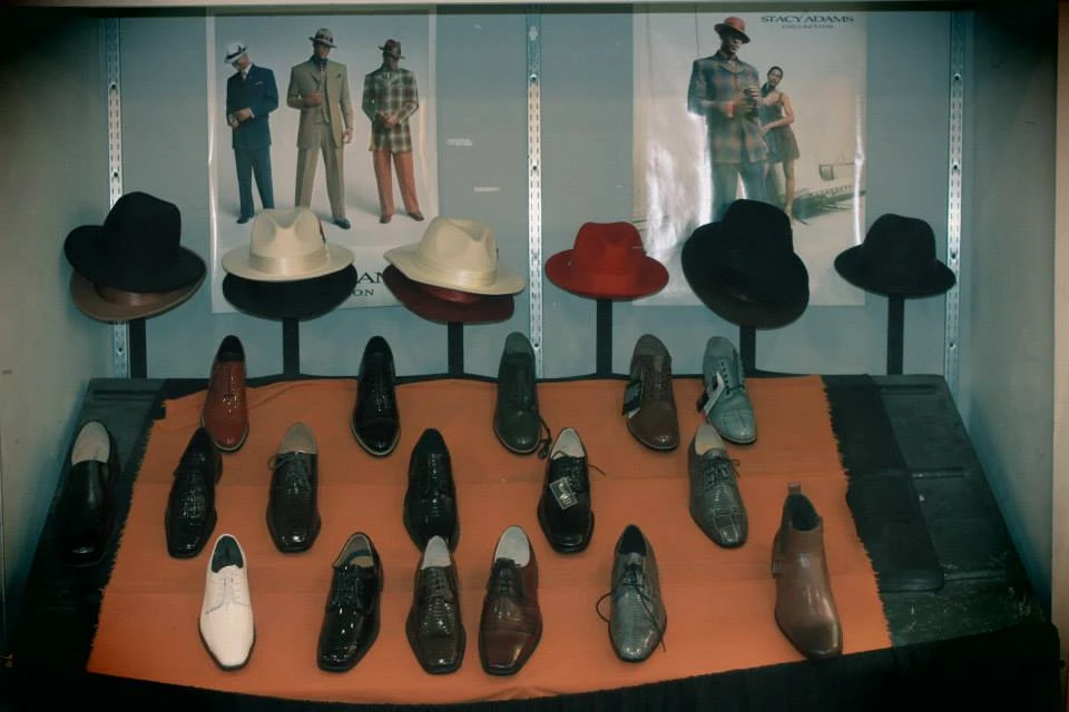 Display of classic fedora hats in black, white, cream, and red with dress shoes