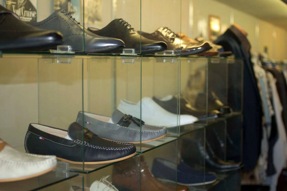Glass shelf display of loafers and oxford dress shoes